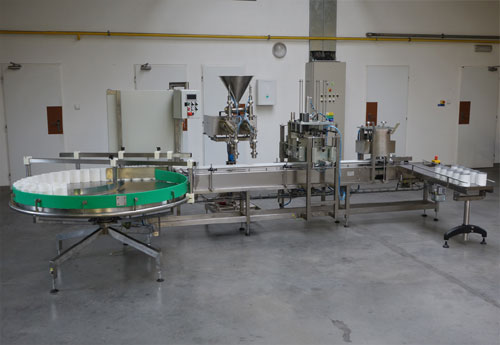 Plnicí linka s válečkovou tratí, víčkováním, akumulačním stolem